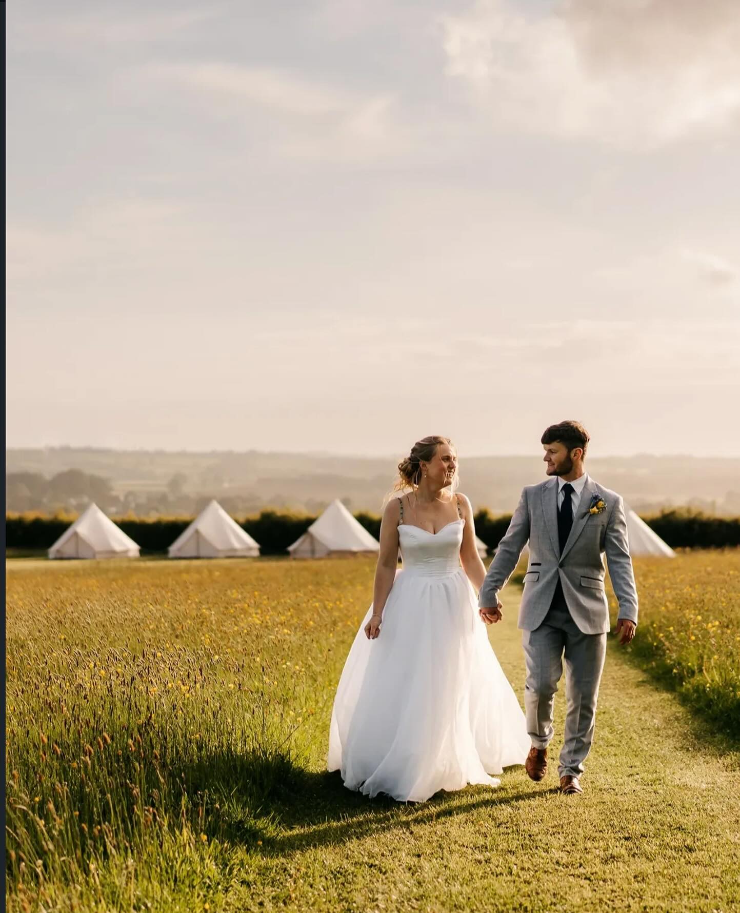 Newly married couple in a meadow beside the bell tents